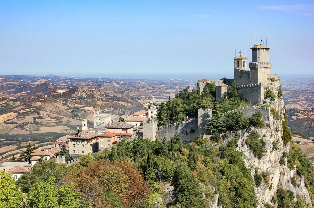 Tradycyjne pamiątki z San Marino: wino Sangiovese, miód i ceramiczna płytka na tle malowniczego krajobrazu Apeninów.